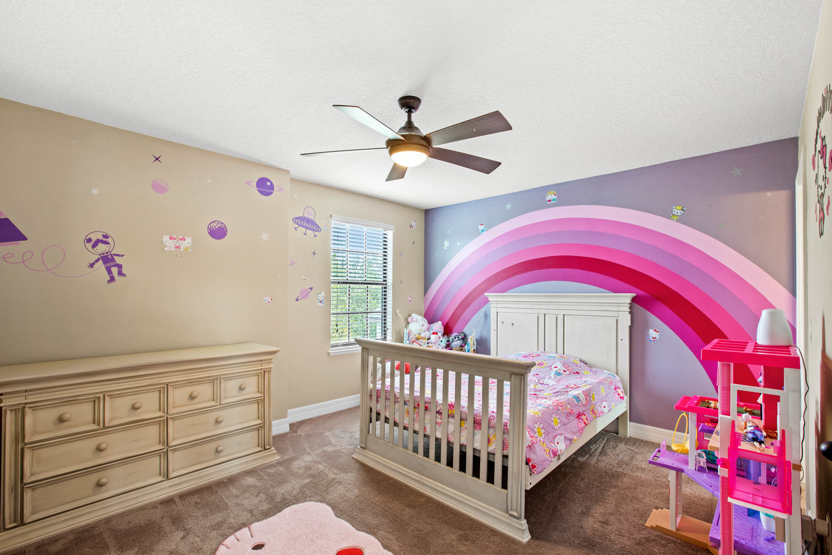 bedroom with pink rainbow on wall and little girl decor
